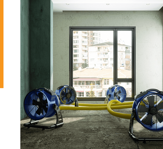 Group 9 (3) Three large industrial fans with yellow ducts are set up in an empty room with concrete floors and a window overlooking several apartment buildings.